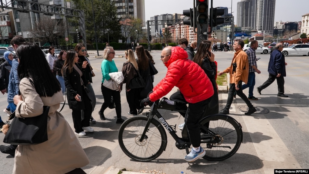 Një qytetar duke kaluar zebrat me biçikletën e tij. Transporti me biçikleta, trotinetë elektrikë dhe vetura elektrike ndihmon në ruajtjen e mjedisit. Ndërkaq, ngasja e biçikletave po ashtu ofron përfitime shëndetësore.