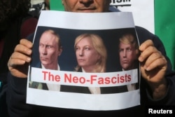 Противник Марин Ле Пен держит плакат с изображением Ле Пен, Владимира Путина и Дональда Трампа и надписью "Неофашисты"