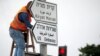 Рабочий устанавливает дорожный знак "Посольство США" на улице в Иерусалиме 
