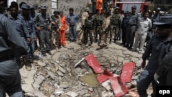 Afghan security officials stand beside a crater at the scene of a bomb and gun attack on the Afghan Parliament in Kabul on June 22.