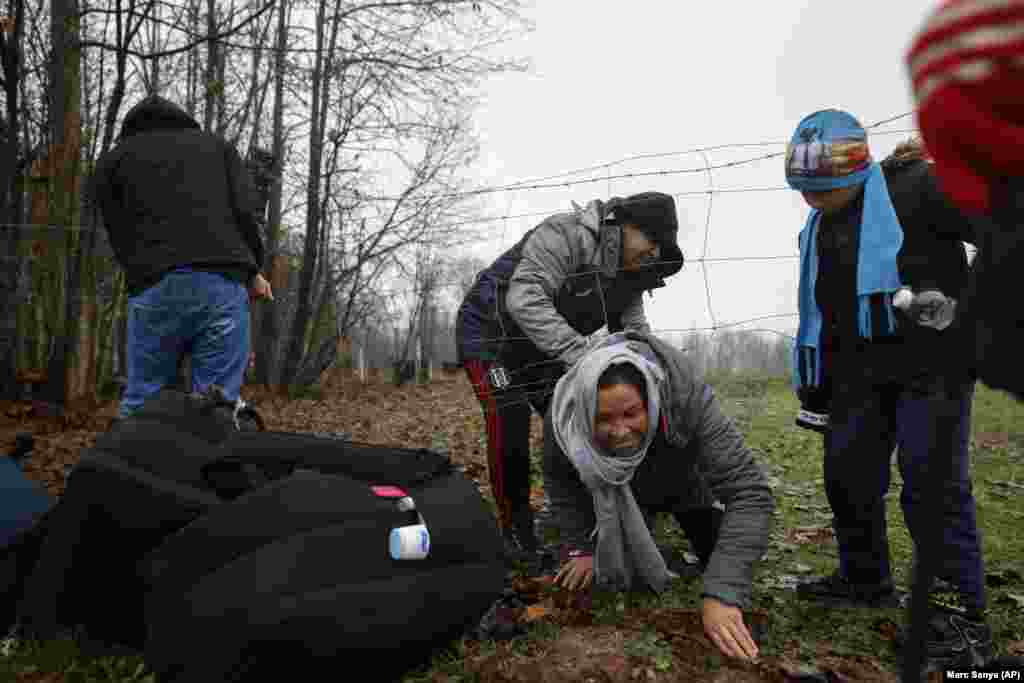 Malika from Afghanistan is helped by her husband, Ahmed, to crawl under a fence a few kilometers from the Bosnian-Croatian border near Velika Kladusa. A statement by the EU&#39;s Bosnia mission says current weather conditions are putting at risk the lives of more than 3,000 people sleeping rough or staying in inadequate conditions. (AP/Marc Sanye)
