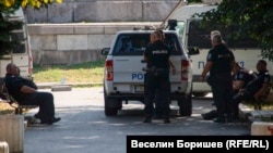 Униформени полицаи си почиват на сянка по време на охрана на мероприятие в центъра на София, август 2023 г.