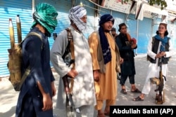 Taliban fighters stand guard in Kunduz City in northern Afghanistan on August 9.