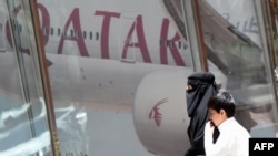 A Saudi woman and a boy walk past the Qatar Airways branch in the Saudi capital, Riyadh, after it had suspended all flights to Saudi Arabia.