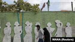 IRAN -- Iranians wearing face masks walk on a street after Iranian authorities made it mandatory for all to wear face masks in public following the outbreak of the coronavirus disease (COVID19), in Tehran, October 10, 2020