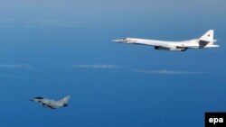 An RAF Typhoon fighter aircraft (left) flies close to a Russian strategic Tupolev TU-160 bomber in September 2015.
