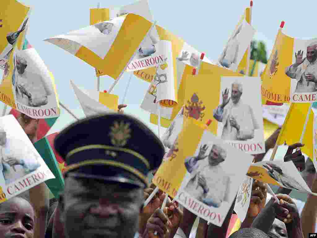 Schoolchildren wave flags showing Pope Benedict in Cameroon during his visit in March 2009.