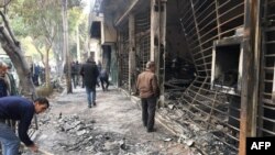 Iranians walk past a charred bank that was set ablaze by protesters during a demonstration against a rise in gasoline prices in the central city of Isfahan on November 17.