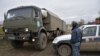 NAGORNO-KARABAKH -- A Karabakh Armenian police officer patrols as a truck of Russian peacekeeping forces moves past him at their checkpoint outside Askeran, November 20, 2020