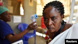 Un angajat medical măsoară temperatura pacientului la un spital în Goma, în cadrul campaniei de monitorizare anti-ebola, 15 iulie 2019
