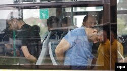 Turkish plainclothes policemen accompany soldiers, who have been detained following a failed coup attempt on July 15 , on a bus as they arrive at an Istanbul court on July 20.
