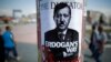 People walk past a poster depicting Prime Minister Recep Tayyip Erdogan that has been pasted by demonstrators on Taksim Square in Istanbul on June 5.