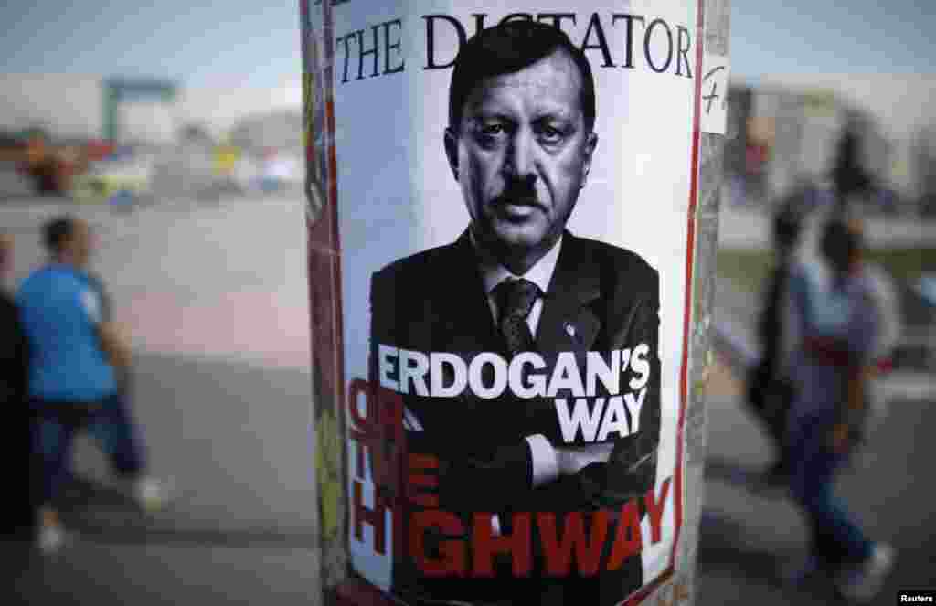 People walk past a poster depicting Prime Minister Recep Tayyip Erdogan that has been pasted by demonstrators on Taksim Square in Istanbul on June 5.
