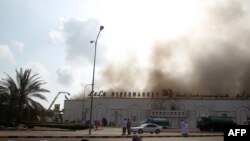 Protesters sit near a burning hypermarket during a demonstration in Sohar on February 27.