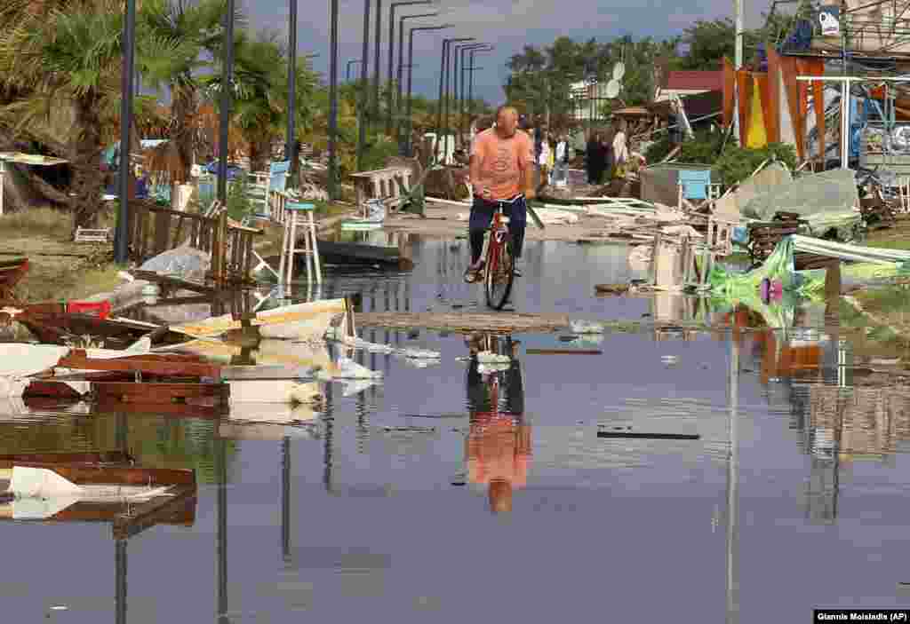 A man rides a bicycle among debris after a storm in the village of Nea Plagia in the Halkidiki region of northern Greece on July 11. At least five people were killed, including a Russian man and his son and a woman from Romania, as violent hail storms battered tourist areas in Greece. (AP/Giannis Moisiadis)