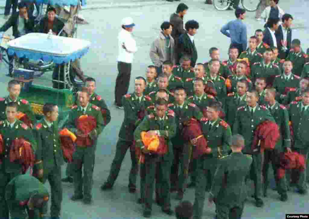 Китайские полицейские побритые как монахи и с монашеским облачением в руках, Лхасу