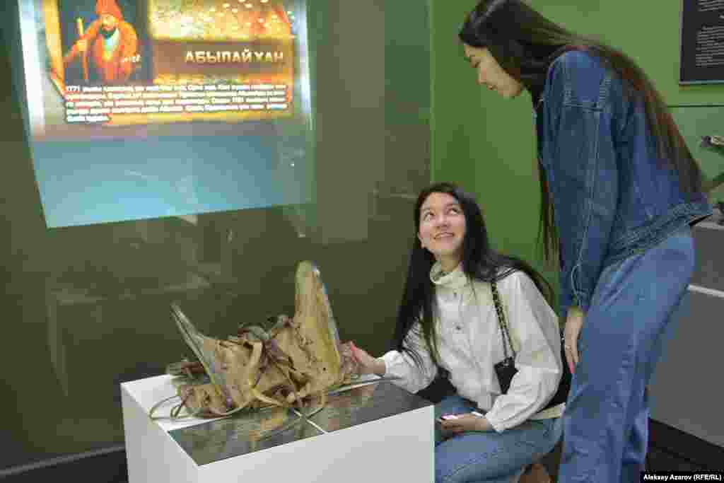 Сагынаш (слева) и Акбопе рассматривают в музее Алматы старинное седло. Девушки являются студентками-третьекурсницами. Об акции «Ночь музеев» в музее Алматы они узнали из Instagram, и им захотелось посетить это мероприятие. За время пребывания в Алматы это их первое посещение музеев. Но в родных городах они бывали в музеях. Одна приехала из Сатпаева, другая – из Аягоза. Алматы, 17 мая 2019 года. 