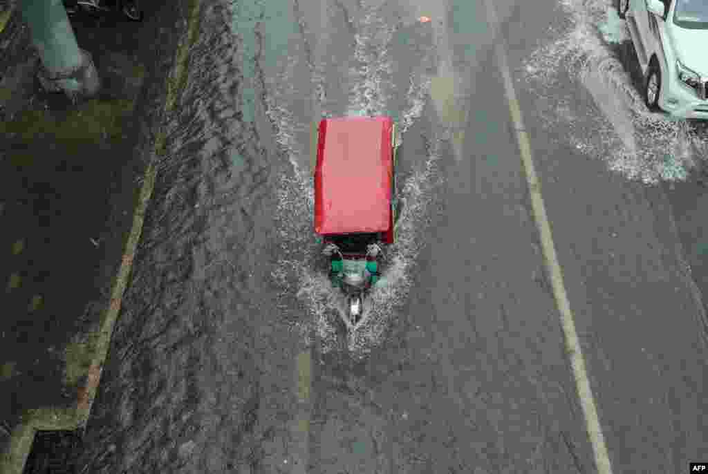 A tricycle makes its way along a flooded street in Beijing, which was hit with heavy rains this week. (AFP)