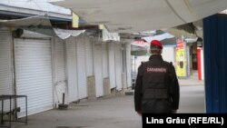  Carabinier patrulând lângă Piața centrala din Chișinău închisă ca urmare a strategiei de încetinire a răspândirii pandemiei de coronavirus.