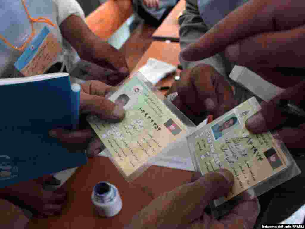 Election commission staff compare a fake voter card with an original at a polling station in Kabul.