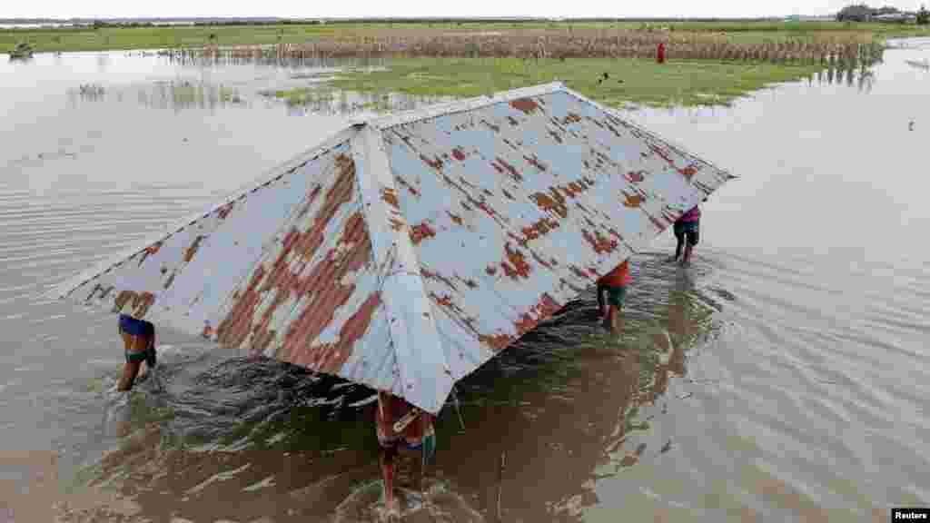 Rokonok és szomszédok segítenek Kosim Uddinnak, hogy átköltöztesse házát a Brahmaputra folyó egyik szigetéről egy másikra, mivel a víz okozta erózió miatt az veszélybe került
