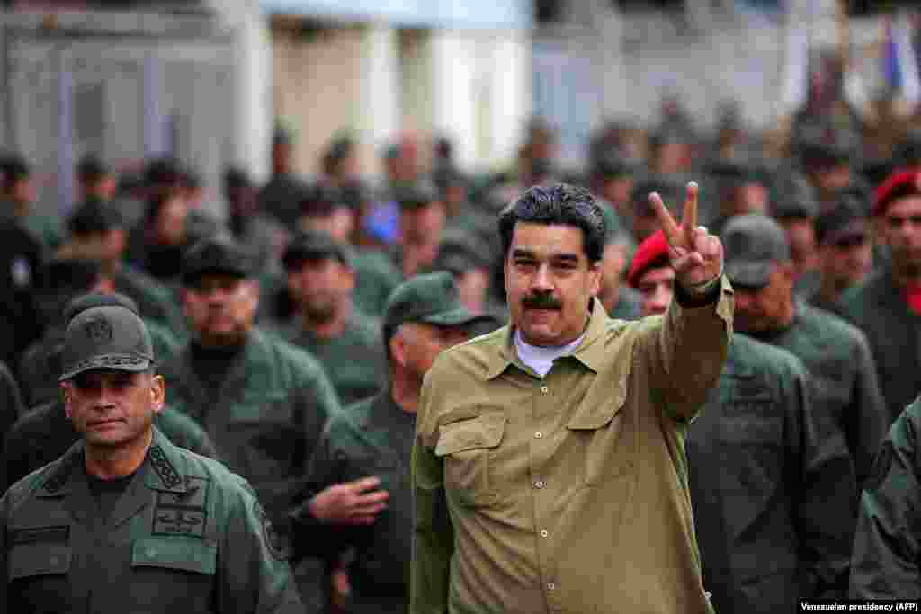 Embattled Venezuelan President Nicolas Maduro flashes the V-sign during a military rally in Caracas on January 30. Opposition leader Juan Guaido has declared himself the country&#39;s legitimate president after elections earlier this month. The United States has also recognized him as such. (AFP/Marcelo Garcia/Venezuelan presidency)