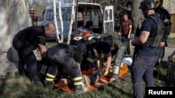 Salvatorii ucraineni transportă cadavrul unei persoane ucise în timpul atacurilor aeriene ruse, în satul Lyptsi, regiunea Harkov. 10 aprilie 2024.