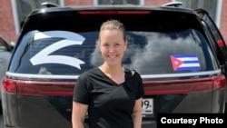 In an undated social media image, Yelena Smirnova, a travel agent from Ryazan, is seen in front of a car showing a Cuban flag and the letter "Z"-- a symbol for Russia's war on Ukraine.