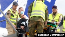 Волонтери програми медичної евакуації допомагають висаджувати пораненого українця з літака в Осло, Норвегія, 16 травня 2023 року.
