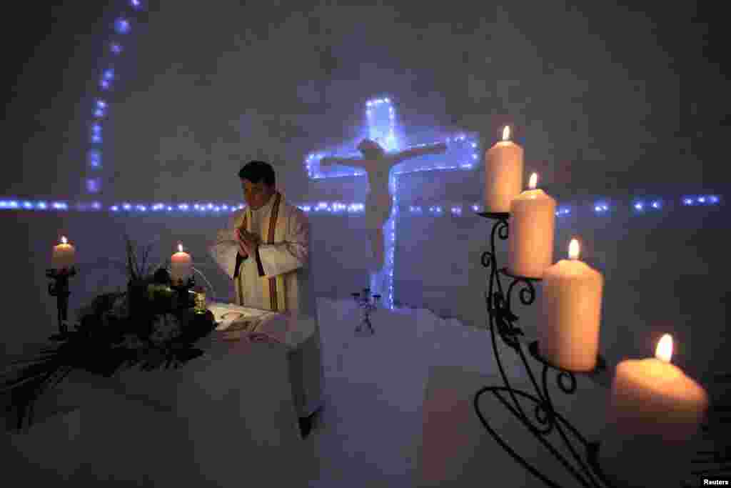 Franciscan monk Iulian Misariu prays during the inaugural mass for a church made entirely from ice at the Balea Lac resort in the Fagaras mountains in Romania on January 29. (Reuters/​Radu Sigheti)