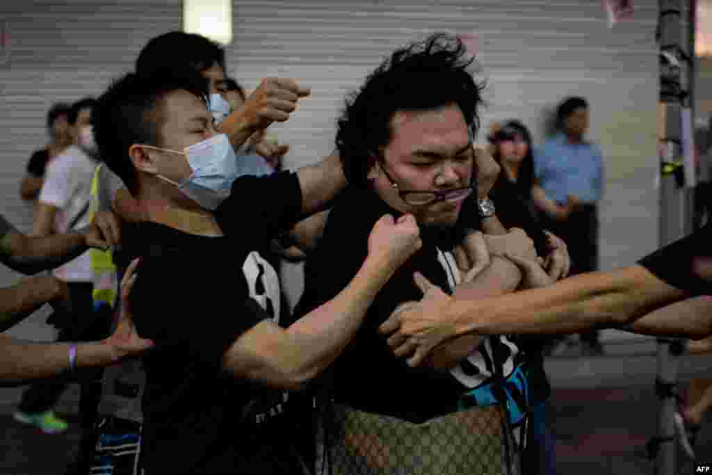 A group of men in masks rough up a man who tried to stop them from removing barricades from a pro-democracy protest area in Hong Kong. Hong Kong has been plunged into the worst political crisis since its 1997 handover as pro-democracy activists take over the streets following China's refusal to grant citizens full universal suffrage. (AFP/Alex Ogle)