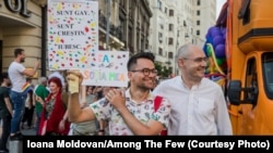 Victor Ciobotaru (stânga) și Florin Buhuceanu (dreapta), cu o pancartă pe care scrie „Sunt gay. Sunt creștin. Iubesc.”, la Bucharest Pride, în București, România, iunie 2019.