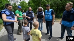 The United Nations' humanitarian coordinator for Ukraine, Denise Brown, (third right) and other UN officials talk to chilren while visited the flood-stricken city of Kherson in southern Ukraine on June 10.