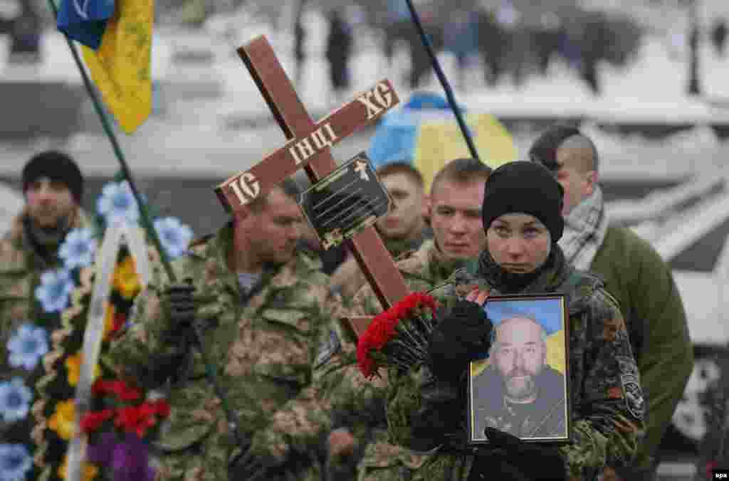 Bohdanna Nikonenko holds a portrait of her father Serhiy as she takes part in a funeral ceremony for the serviceman from the &quot;Aydar&quot; battalion, who was killed in &nbsp;fighting in eastern Ukraine, on Independence Square in Kyiv on January 20. (epa/Sergey Dolzhenko)