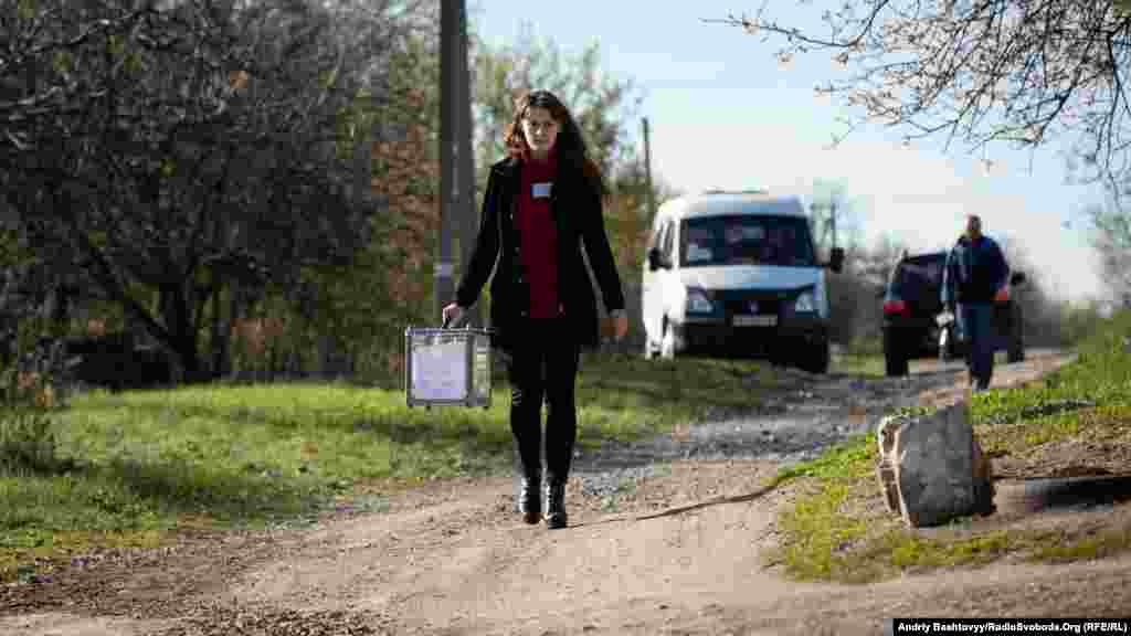 An election official tours the front-line village of Novotroitse in the Donetsk region.