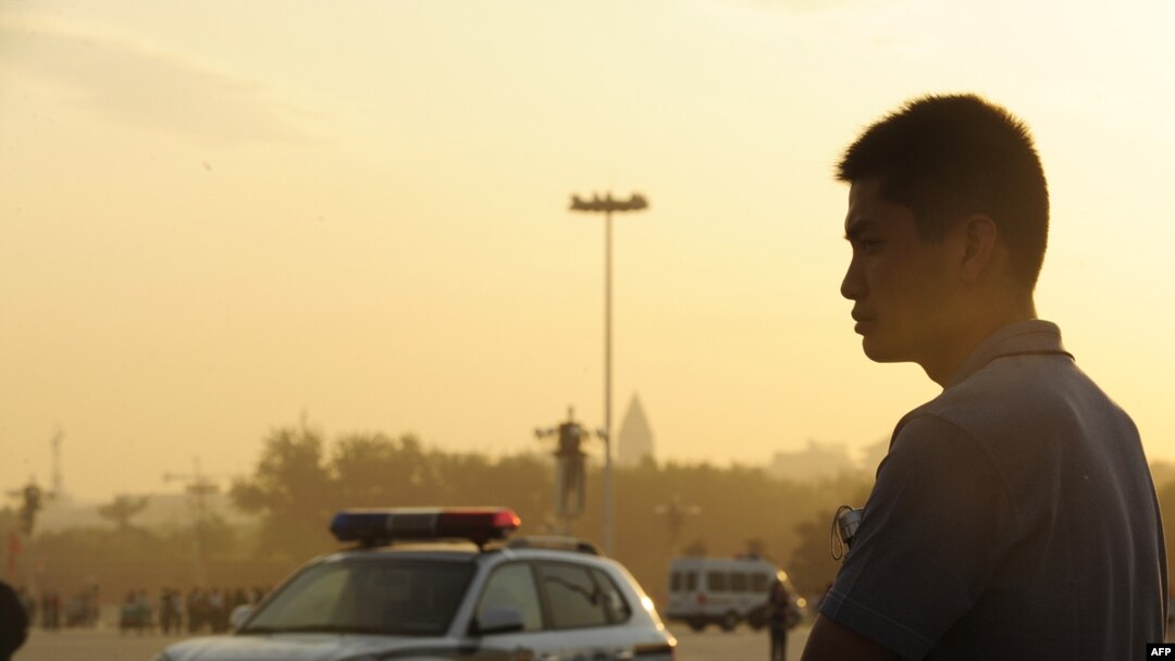 A plainclothes policeman keeps watch on Tiananmen Square at sunrise in Beijing.