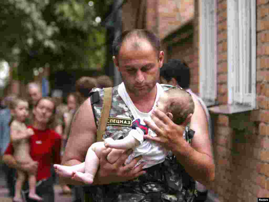  A Russian police officer carries a released baby from the school seized by heavily armed masked men and women in the town of Beslan in the province of North Ossetia near Chechnya, September 2, 2004. REUTERS/Viktor Korotayev 