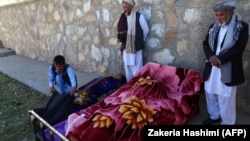 Afghan men stand over dead bodies at the site of an attack by Taliban militants on a government compound in the Khwaja Omari district in Ghazni Province on April 12.