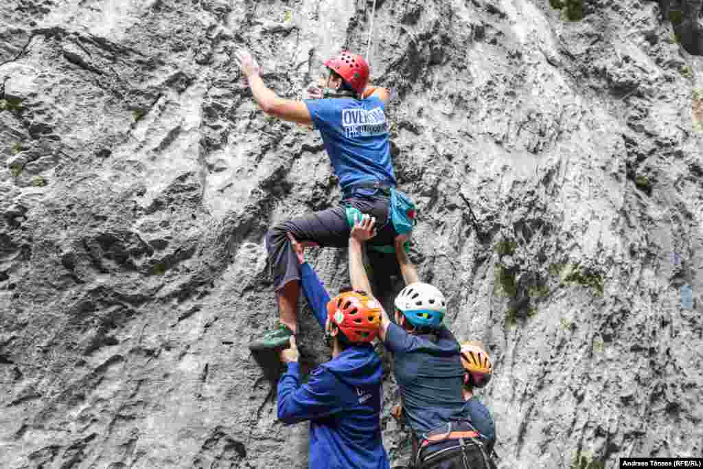 Sportivi Climb Again îl ajută pe unul dintre colegi șă avanseze pe un traseu de escaladă, în timpul cantonamentului din Cheile Sohodolului.