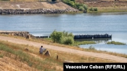 Un bărbat pictează un peisaj cu Nistrul, în apropiere de Centrala hidroelectrică de la Dubăsari.