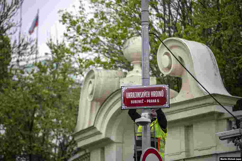 A street sign naming a stretch of road Ukrainian Heroes Street is installed in front of the Russian Embassy (visible at top left) in Prague in April 2022.