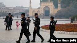 Сотрудники службы безопасности патрулируют территорию возле мечети в Кашгаре, городе в Синьцзяне