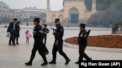 Сотрудники сил безопасности патрулируют площадь перед мечетью в Кашгаре, городе в Синьцзяне. Ноябрь 2017 года.