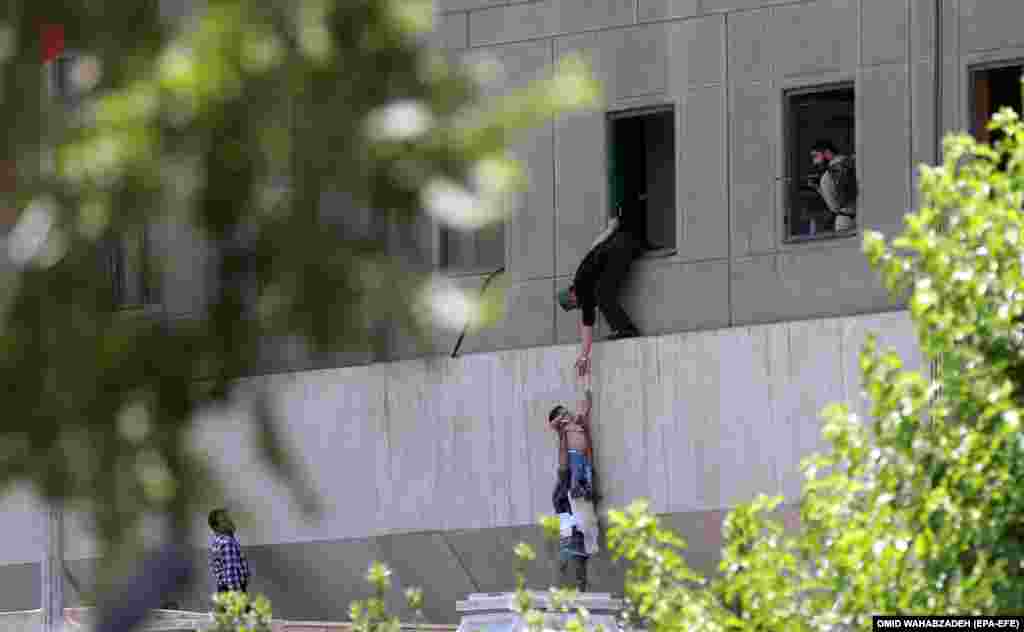 Iranian policemen help civilians flee the parliament building in Teheran. At least 12 people were killed in twin attacks on parliament and the tomb of Iran&#39;s former supreme leader Ayatollah Khomeini. June 7, 2017. (EPA-EFE/Omid Wahabzadeh)