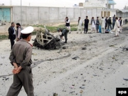 Polițiștii afgani inspectează resturile unei mașini folosite într-un atac sinucigaș cu bombă asupra trupelor canadiene din Kandahar, 30 martie 2006. Bomba a explodat înainte de a ajunge în dreptul convoiului, ucigând sinucigașul și rănind șapte civili.