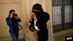 Аиша Мера, сестра Мохамеда Мера, который убил семь человек на юго-западе Франции в 2012 году, скрывает лицо, когда прибывает 16 октября 2017 года в здание суда Парижа, где проходит процесс над другим ее братом, обвиненным в соучастии