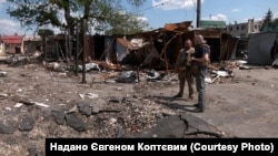 Євген Коптєв (п.) та представник «Білих янголів» в центрі Васильківки, який зазнав руйнувань через атаки КАБами