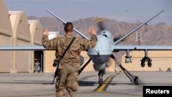 A U.S. airman guides a US Air Force MQ-9 Reaper drone as it taxis to the runway at Kandahar airfield in March.