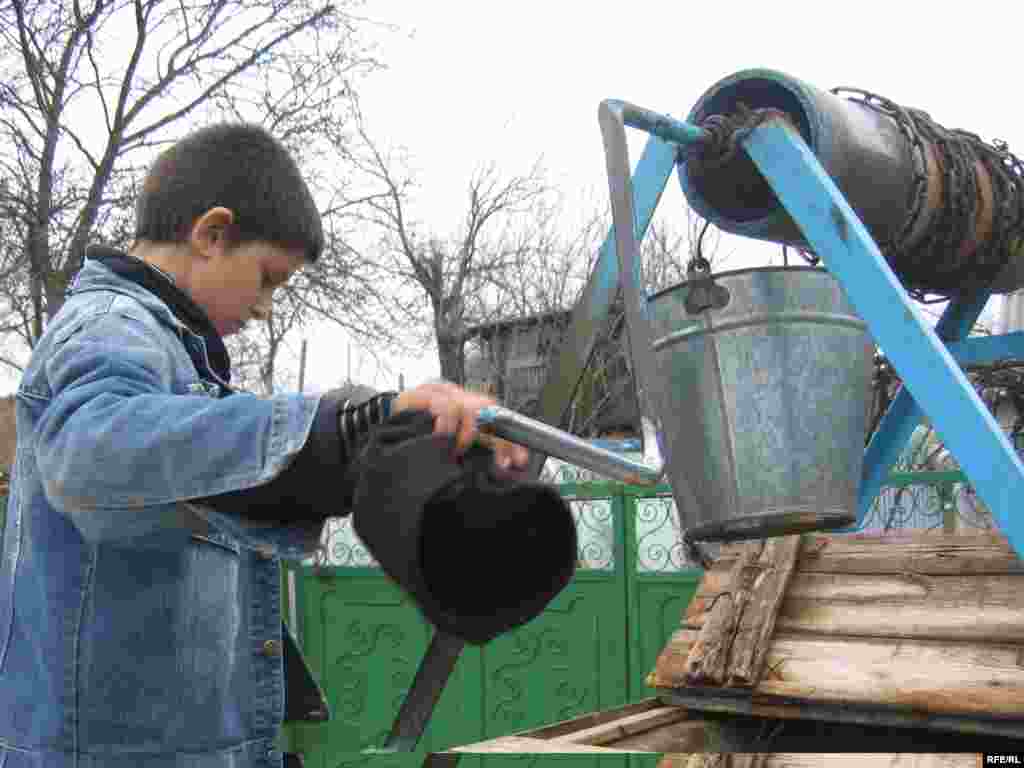 Vasilica Bejan draws water from a well. While life is hard at home, he's happier there than in the orphanage.