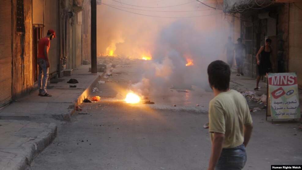 Dy njerëz duke e shikuar zjarrin nga të shtënat në Alepo të Sirisë